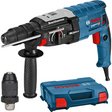 Ein blau-schwarzer Bosch Professional GBH 2-28 F Bohrhammer mit seitlichem Griff, zusätzlichem SDS-plus Bohrfutter und einem blauen Bosch-Koffer daneben.