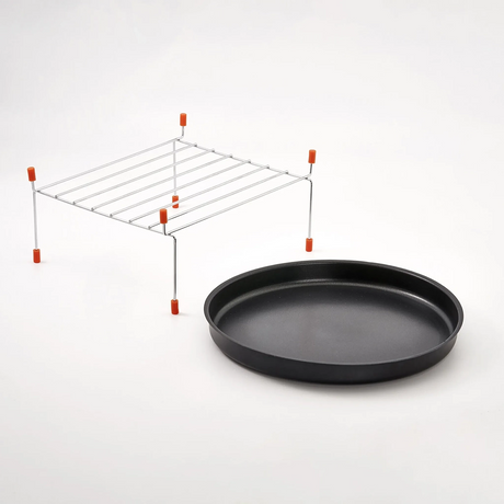 Ein schwarzes, rundes Backblech und ein Metallgitter mit orangefarbenen Füßen sind nebeneinander abgebildet, ideal für die CASO HCMG 25 Mikrowelle - silber von CASO, alles vor einem schlichten weißen Hintergrund.