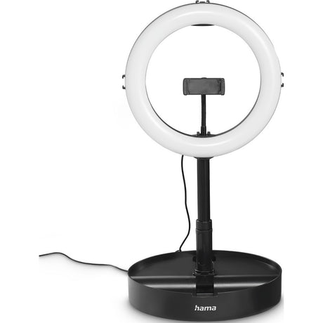 Die Hama LED-RGB-Ringleuchte SpotLight FoldUp RGB ist eine kreisförmige LED-Ringleuchte mit Telefonhalterung, montiert auf einem schwarzen, verstellbaren Ständer. Es hat ein RGB-Studio-freundliches Design, einen breiten Sockel mit dem Hama-Logo und wird mit einem Netzkabel geliefert.